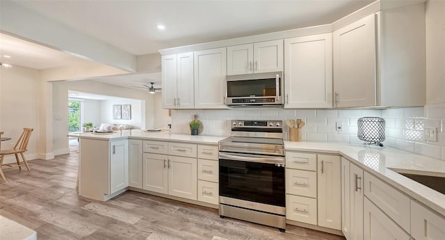 2825 Pinecrest St, Sarasota, FL 34239 - kitchen featuring appliances with stainless steel finishes, a peninsula, tasteful backsplash, white cabinetry, and recessed lighting