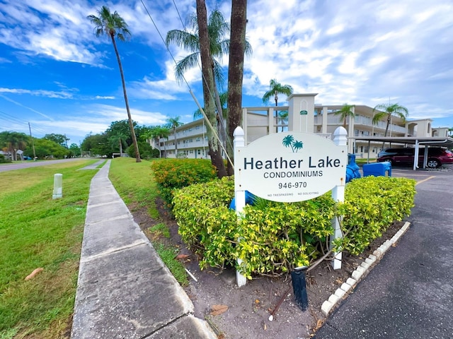 community sign with a lawn and covered parking