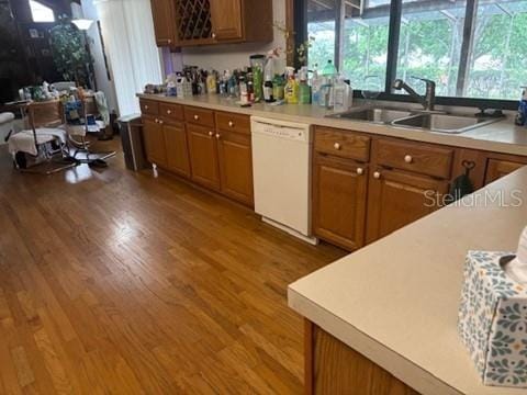 1212 Candlewood Dr, Lakeland, FL 33813 - kitchen featuring white dishwasher, a sink, wood finished floors, brown cabinets, and light countertops