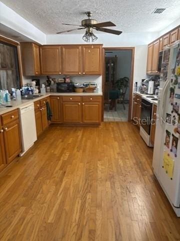 1212 Candlewood Dr, Lakeland, FL 33813 - kitchen with white appliances, ceiling fan, light wood-style flooring, brown cabinets, and a textured ceiling