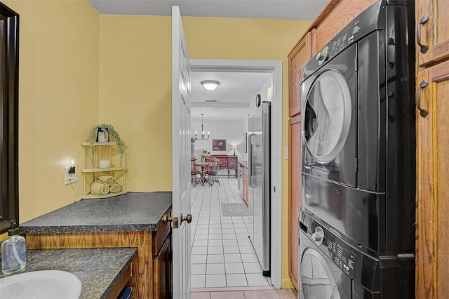 2708 27th Avenue Dr W, Bradenton, FL 34205 - washroom with stacked washing machine and dryer, light tile patterned flooring, and a chandelier