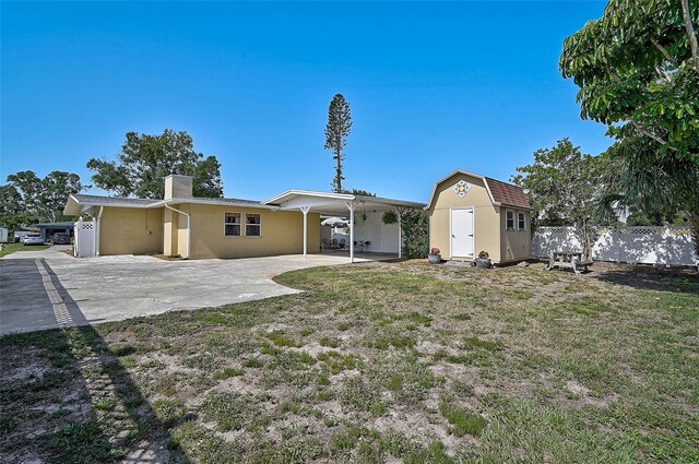 2708 27th Avenue Dr W, Bradenton, FL 34205 - rear view of property featuring a shed, a chimney, driveway, an attached carport, and stucco siding