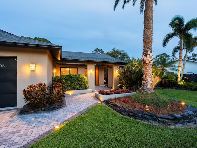3905 Country View Dr, Sarasota, FL 34233 - view of front of house featuring stucco siding, a front lawn, a shingled roof, and an attached garage