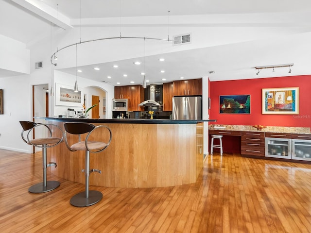 3905 Country View Dr, Sarasota, FL 34233 - kitchen featuring stainless steel appliances, wall chimney exhaust hood, modern cabinets, light wood-type flooring, and a kitchen breakfast bar