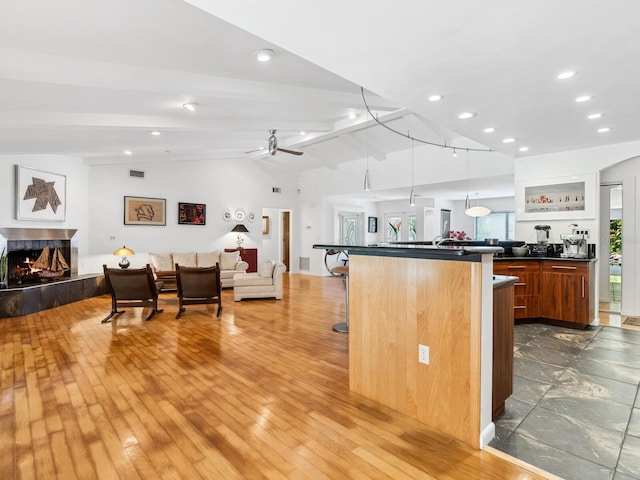3905 Country View Dr, Sarasota, FL 34233 - kitchen with open floor plan, dark countertops, a tiled fireplace, a kitchen breakfast bar, and a ceiling fan