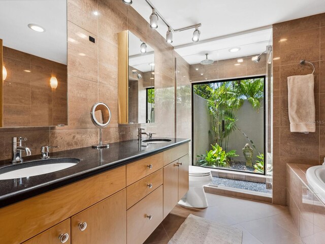 3905 Country View Dr, Sarasota, FL 34233 - bathroom featuring tile walls, tile patterned flooring, double vanity, a relaxing tiled tub, and toilet