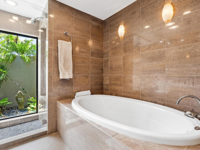 3905 Country View Dr, Sarasota, FL 34233 - bathroom featuring a garden tub, tile patterned flooring, and tile walls
