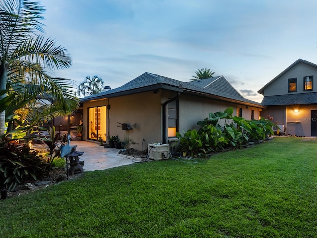 3905 Country View Dr, Sarasota, FL 34233 - back of property featuring a yard, stucco siding, a patio, and a shingled roof
