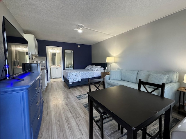 bedroom featuring light wood-type flooring, a textured ceiling, and connected bathroom