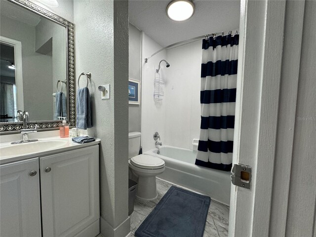 bathroom with a textured wall, marble look tiles, shower / bathtub combination with curtain, vanity, and toilet