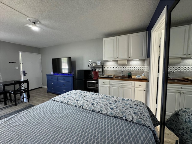 bedroom with a sink, wood finished floors, and a textured ceiling