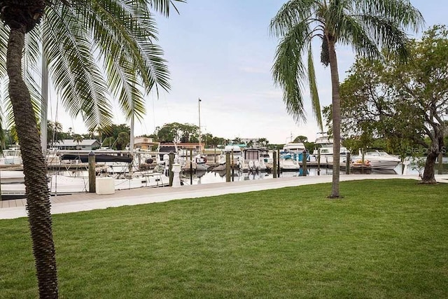 view of community with a lawn, a dock, and a water view