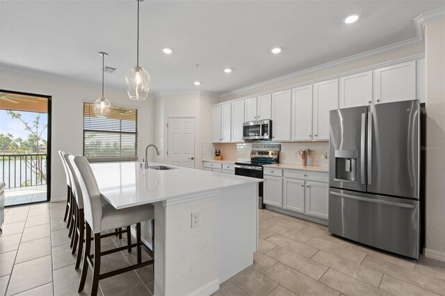 10820 Tarflower Dr Unit 202, Venice, FL 34293 - kitchen featuring appliances with stainless steel finishes, a sink, an island with sink, backsplash, and crown molding
