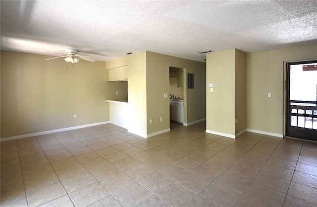 empty room with light tile patterned flooring, ceiling fan, a textured ceiling, and baseboards