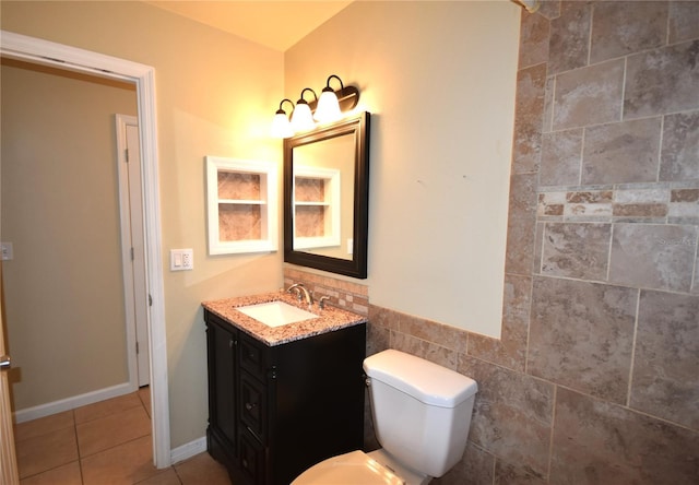 bathroom featuring toilet, vanity, tile patterned flooring, and tile walls