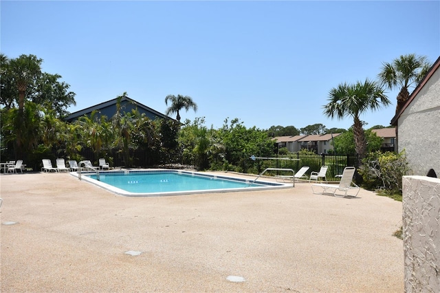 community pool with a patio area and fence