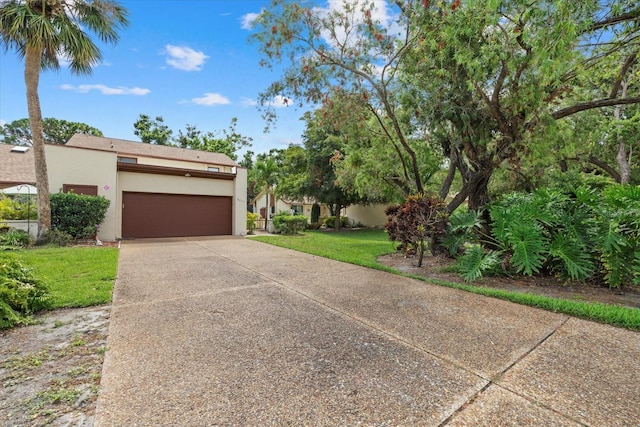 6207 Courtside Dr Unit 23, Bradenton, FL 34210 - view of front of house featuring stucco siding, concrete driveway, an attached garage, and a front lawn