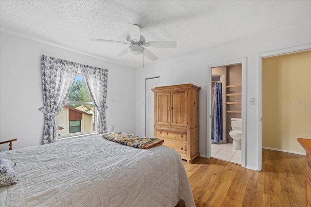 6207 Courtside Dr Unit 23, Bradenton, FL 34210 - bedroom with light wood finished floors, a textured ceiling, baseboards, connected bathroom, and a ceiling fan