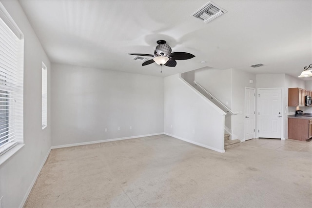 3760 82nd Avenue Cir E Unit 102, Sarasota, FL 34243 - unfurnished living room featuring light colored carpet, stairs, healthy amount of natural light, and a ceiling fan