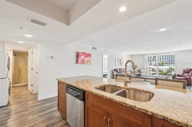 101 S Gulfstream Ave Unit 6C, Sarasota, FL 34236 - kitchen with dishwasher, stacked washer / drying machine, a sink, brown cabinetry, and light wood-style floors
