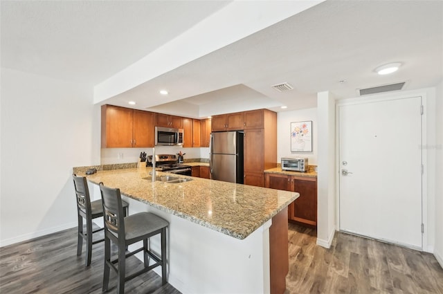 101 S Gulfstream Ave Unit 6C, Sarasota, FL 34236 - kitchen with appliances with stainless steel finishes, a peninsula, wood finished floors, light stone countertops, and a breakfast bar