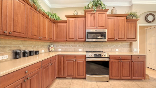 4920 Woodhurst Dr, Sarasota, FL 34243 - kitchen featuring appliances with stainless steel finishes, light countertops, ornamental molding, light tile patterned flooring, and brown cabinets
