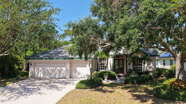4920 Woodhurst Dr, Sarasota, FL 34243 - view of front of property featuring a garage, driveway, french doors, and stucco siding