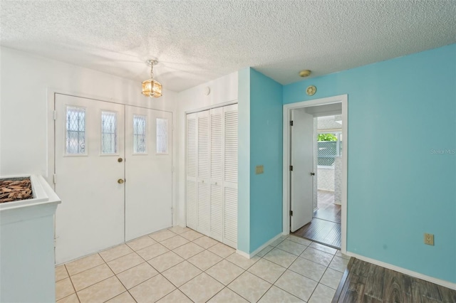 104 Hourglass Dr, Venice, FL 34293 - entryway featuring light tile patterned flooring, a chandelier, a textured ceiling, and baseboards