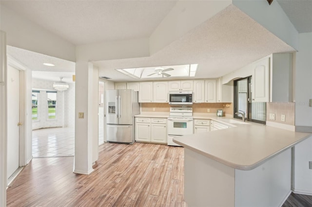 104 Hourglass Dr, Venice, FL 34293 - kitchen with appliances with stainless steel finishes, a sink, a peninsula, light countertops, and a skylight