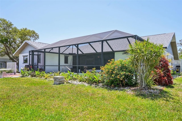 104 Hourglass Dr, Venice, FL 34293 - rear view of property with a lawn, a lanai, roof with shingles, and stucco siding