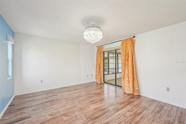 104 Hourglass Dr, Venice, FL 34293 - unfurnished room featuring a chandelier, wood finished floors, and a textured ceiling