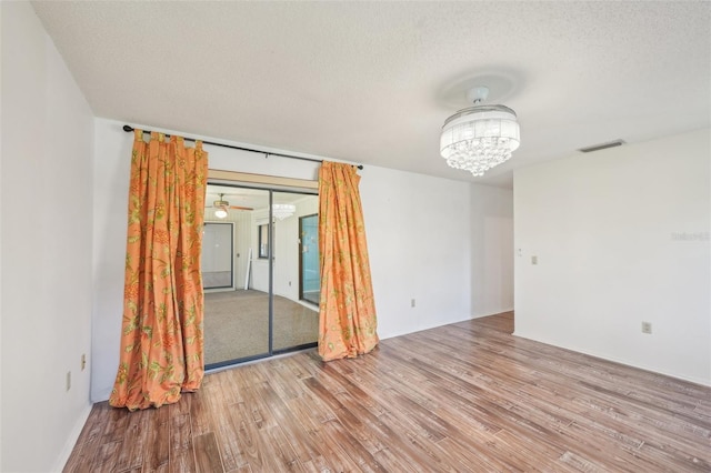 104 Hourglass Dr, Venice, FL 34293 - unfurnished room with wood finished floors, a chandelier, and a textured ceiling