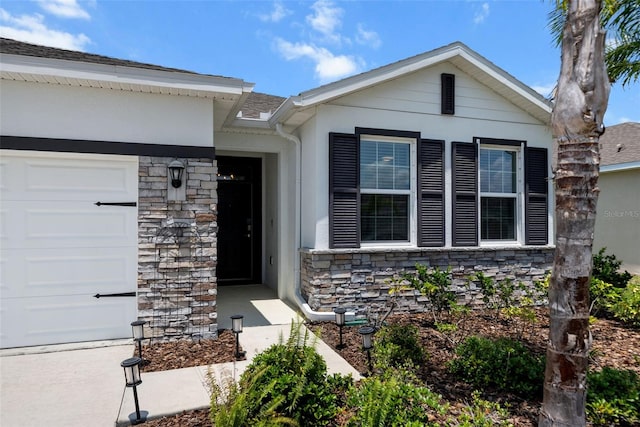 view of front facade featuring stone siding, an attached garage, and stucco siding
