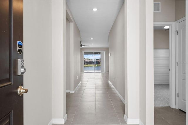 hallway featuring light tile patterned flooring, recessed lighting, a water view, and baseboards