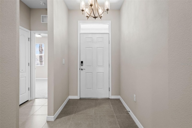 tiled foyer featuring a chandelier and baseboards