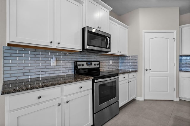 kitchen with stainless steel appliances, white cabinets, tasteful backsplash, dark stone countertops, and light tile patterned floors