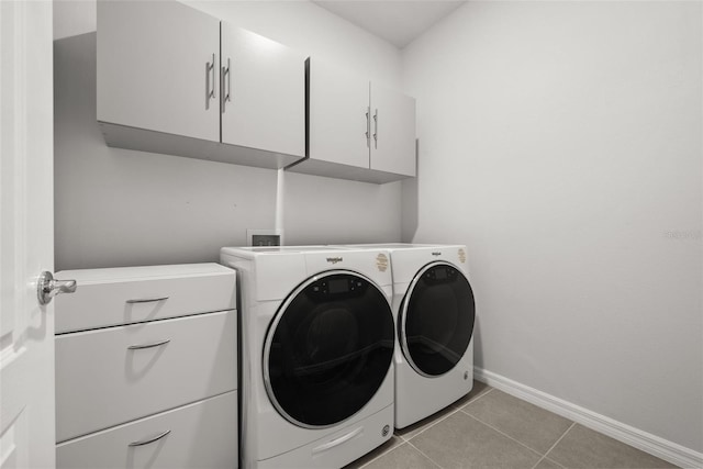 washroom featuring cabinet space, washing machine and dryer, light tile patterned floors, and baseboards