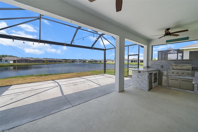 view of patio featuring ceiling fan, exterior kitchen, a water view, grilling area, and glass enclosure