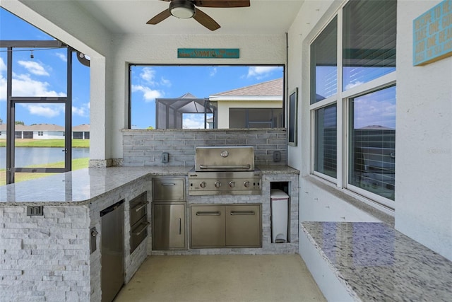 view of patio / terrace featuring a grill, a water view, an outdoor kitchen, and a ceiling fan