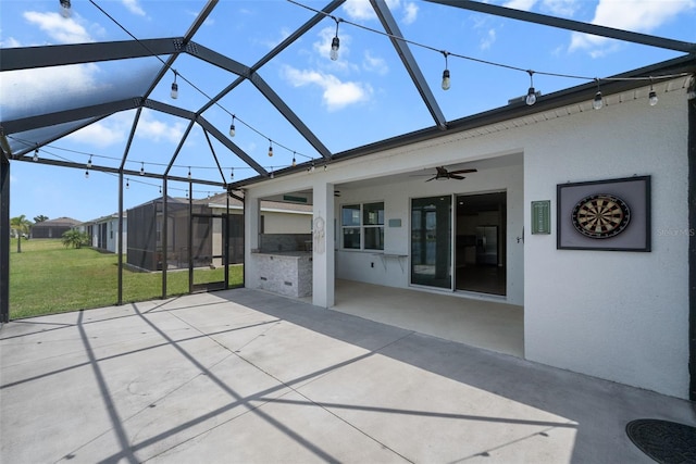 view of patio featuring a ceiling fan, an outdoor kitchen, and glass enclosure