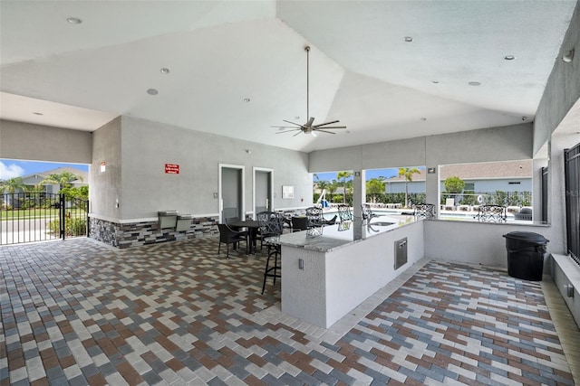 kitchen featuring high vaulted ceiling, a ceiling fan, a peninsula, open floor plan, and a kitchen breakfast bar