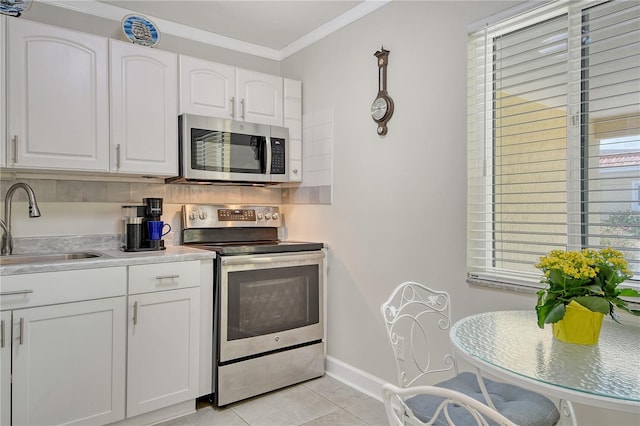 4840 Gulf Of Mexico Dr Unit 15, Longboat Key, FL 34228 - kitchen featuring appliances with stainless steel finishes, a sink, baseboards, white cabinetry, and light tile patterned floors