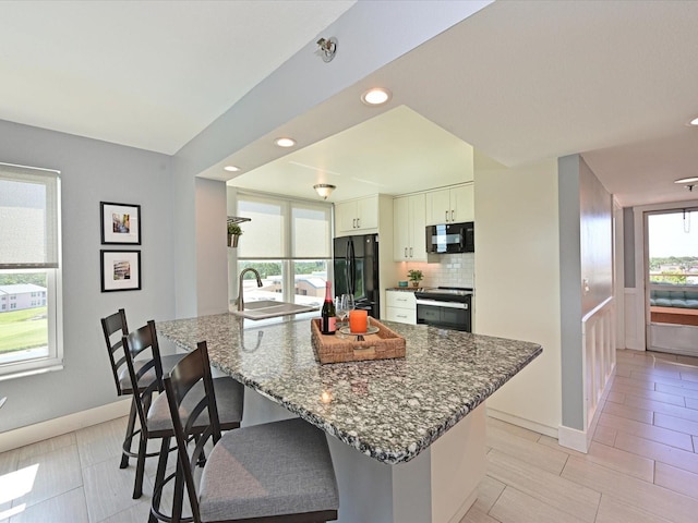 4550 Pinebrook Cir Unit 608, Bradenton, FL 34209 - kitchen featuring black appliances, a breakfast bar, dark stone counters, a sink, and recessed lighting