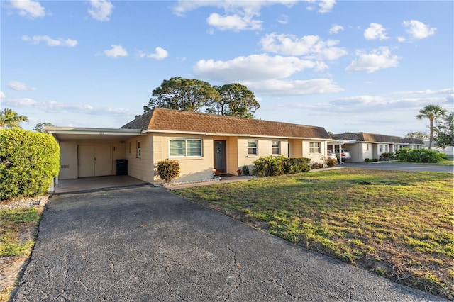 505 47th Avenue Dr W, Bradenton, FL 34207 - ranch-style house with asphalt driveway, concrete block siding, a carport, a front lawn, and a shingled roof