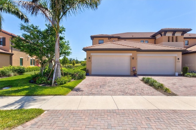 23528 Awabuki Dr Unit 101, Venice, FL 34293 - mediterranean / spanish-style home featuring stucco siding, decorative driveway, a tiled roof, and a garage