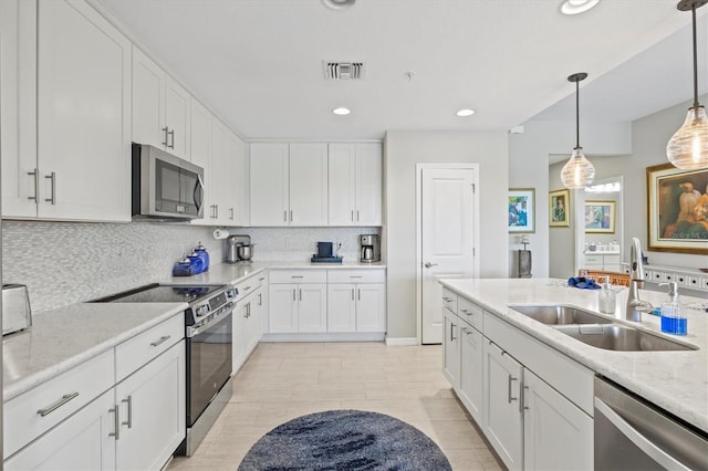 23528 Awabuki Dr Unit 101, Venice, FL 34293 - kitchen with appliances with stainless steel finishes, a sink, tasteful backsplash, white cabinetry, and recessed lighting