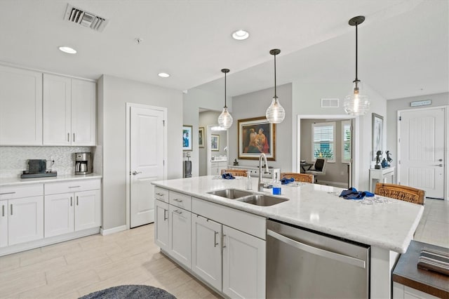23528 Awabuki Dr Unit 101, Venice, FL 34293 - kitchen with stainless steel dishwasher, a sink, white cabinetry, an island with sink, and pendant lighting