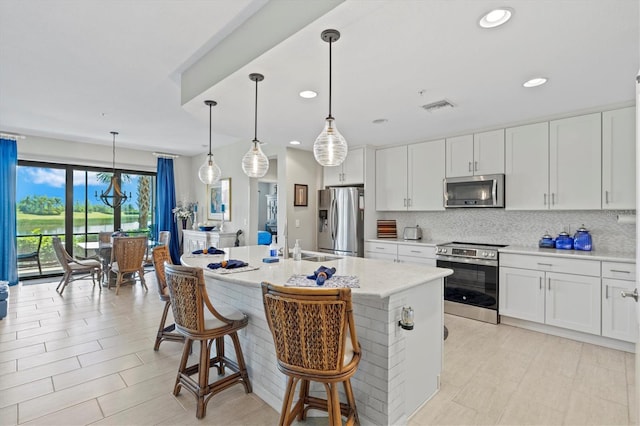 23528 Awabuki Dr Unit 101, Venice, FL 34293 - kitchen featuring appliances with stainless steel finishes, tasteful backsplash, white cabinetry, recessed lighting, and an island with sink
