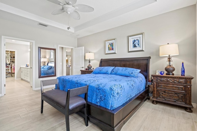23528 Awabuki Dr Unit 101, Venice, FL 34293 - bedroom with a raised ceiling, light wood-type flooring, baseboards, a ceiling fan, and ensuite bath
