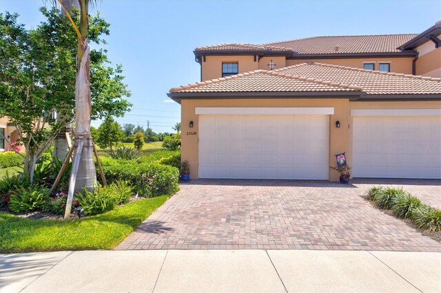 23528 Awabuki Dr Unit 101, Venice, FL 34293 - view of front of house featuring stucco siding, decorative driveway, a garage, and a tile roof